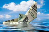 美元折成的纸船掉入水中图片